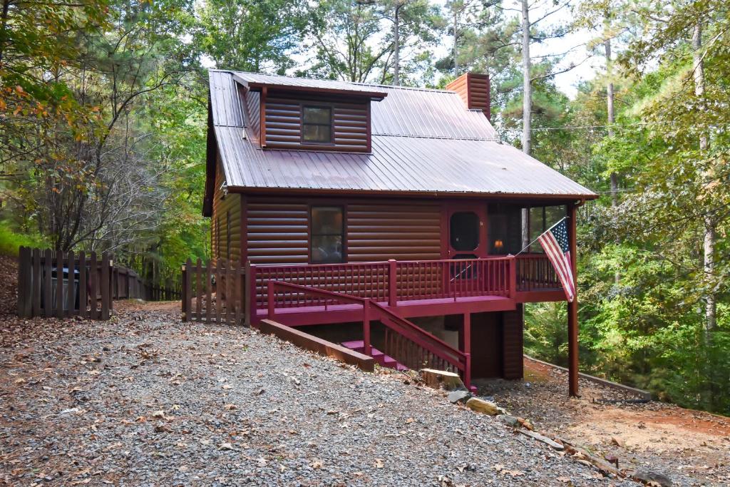 a small cabin in the woods with a red deck at River's Creekside Cabin in Ellijay