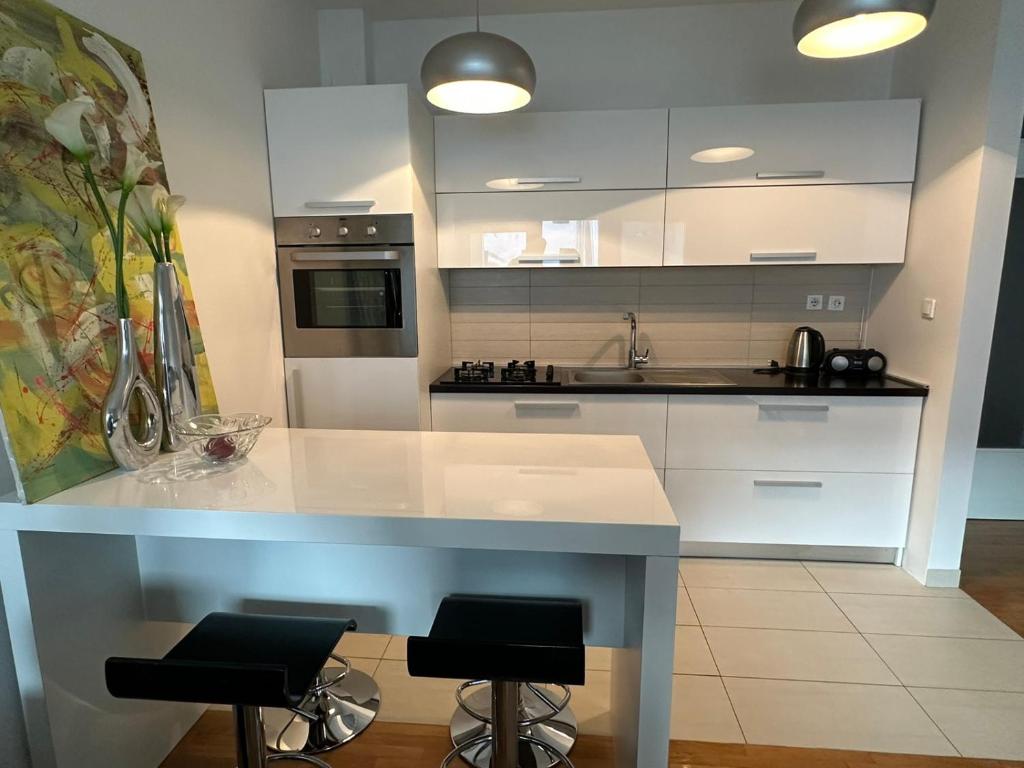 a kitchen with white cabinets and a counter with stools at Studio apartman Luce self CHECK IN in Osijek
