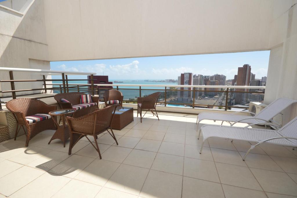 Un balcón con sillas y mesas y vistas al océano. en Leme Penthouse Apartment, en Fortaleza