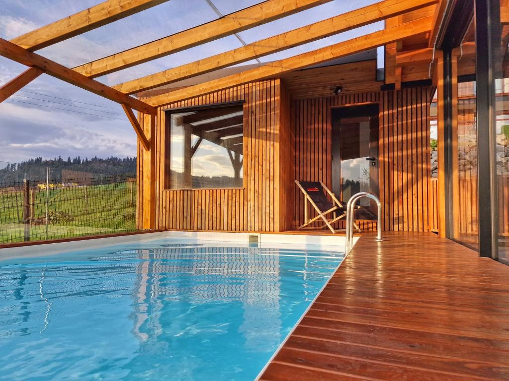 une maison en bois avec une piscine en face de celle-ci dans l'établissement Nad Zalew, à Sromowce Wyżne