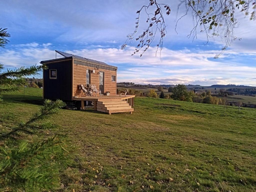 a tiny house in a field with a deck at Maringotka_naluke in Detvianska Huta