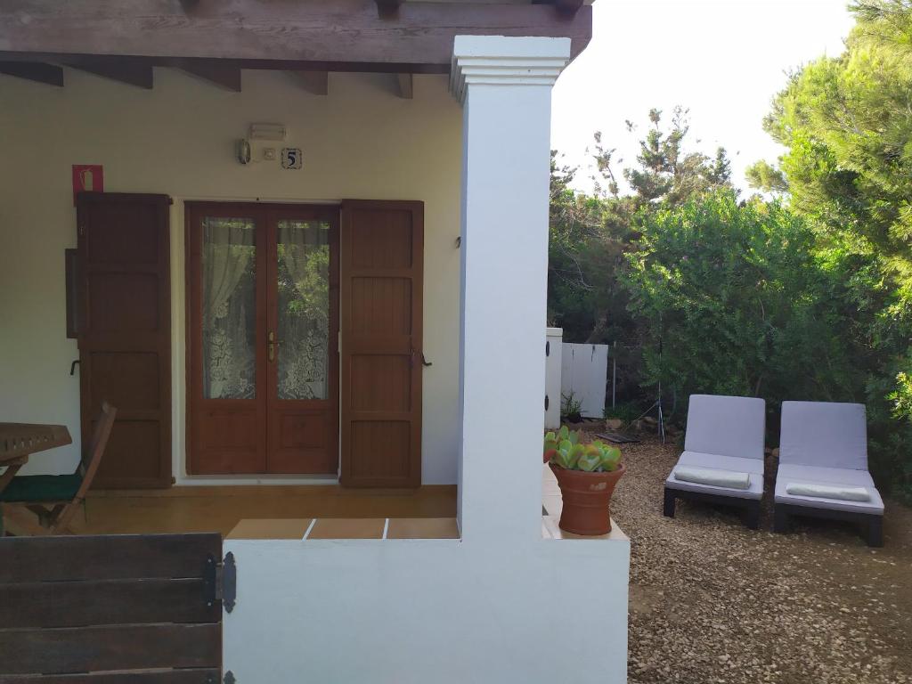 una casa con due sedie bianche davanti a una porta di Ca n'Antonia Mestre a Playa Migjorn