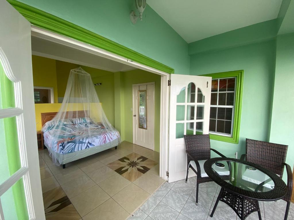 a room with a bed and a table and chairs at Greenhouse on the Hill, Sea View Studio Apartment in Laborie