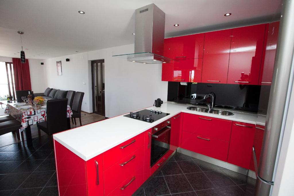 a kitchen with red cabinets and a dining room at Apartments Casablanca in Podstrana