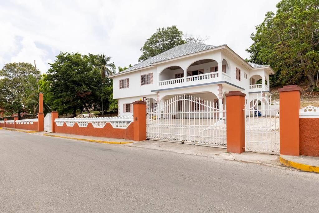 a white house with a fence on the side of a street at Shaw Park Gem Apt 12A in Ocho Rios