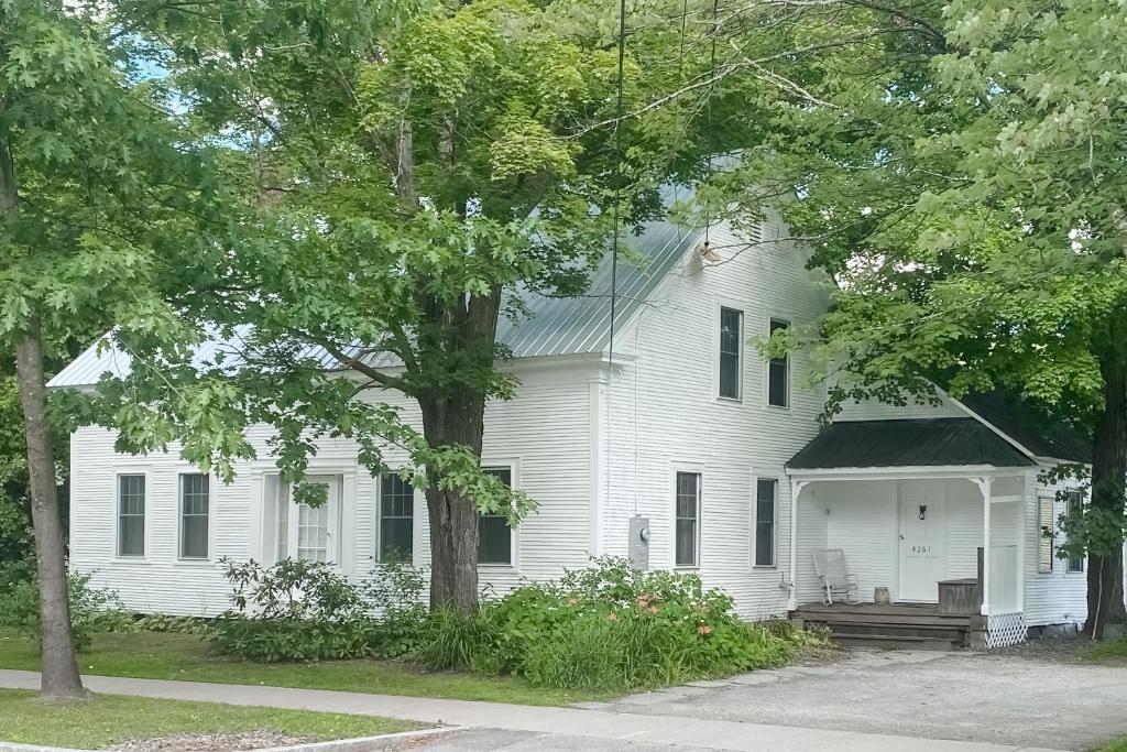 Casa blanca con porche y árbol en Maplewood Haven, en Waitsfield