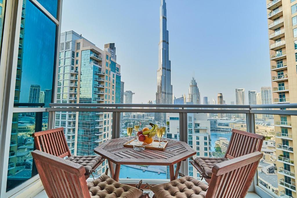 Burj Khalifa Front view & Fountain view Island Paradise 2BR Luxury Apartment Burj residences Golden Homes في دبي: بلكونه مع طاوله وكراسي واطلاله على مدينه