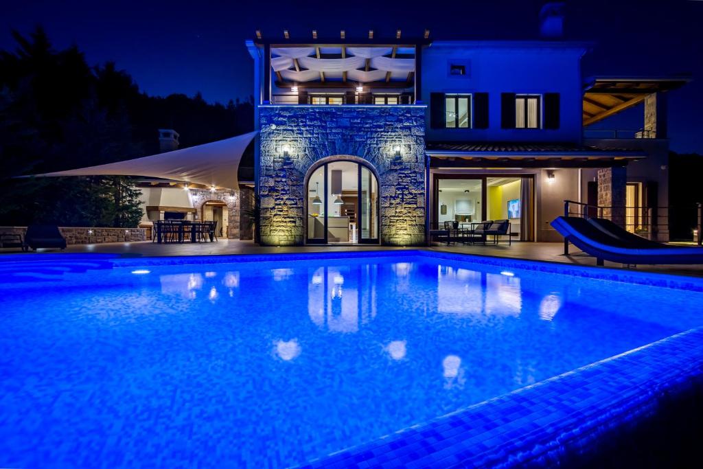 een zwembad voor een huis 's nachts bij Villa Marone in Opatija