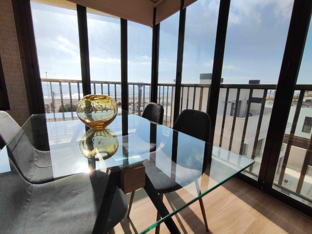 a glass table and chairs in a room with a balcony at Ático Las Minvas 1ª linea de playa in Grao de Castellón