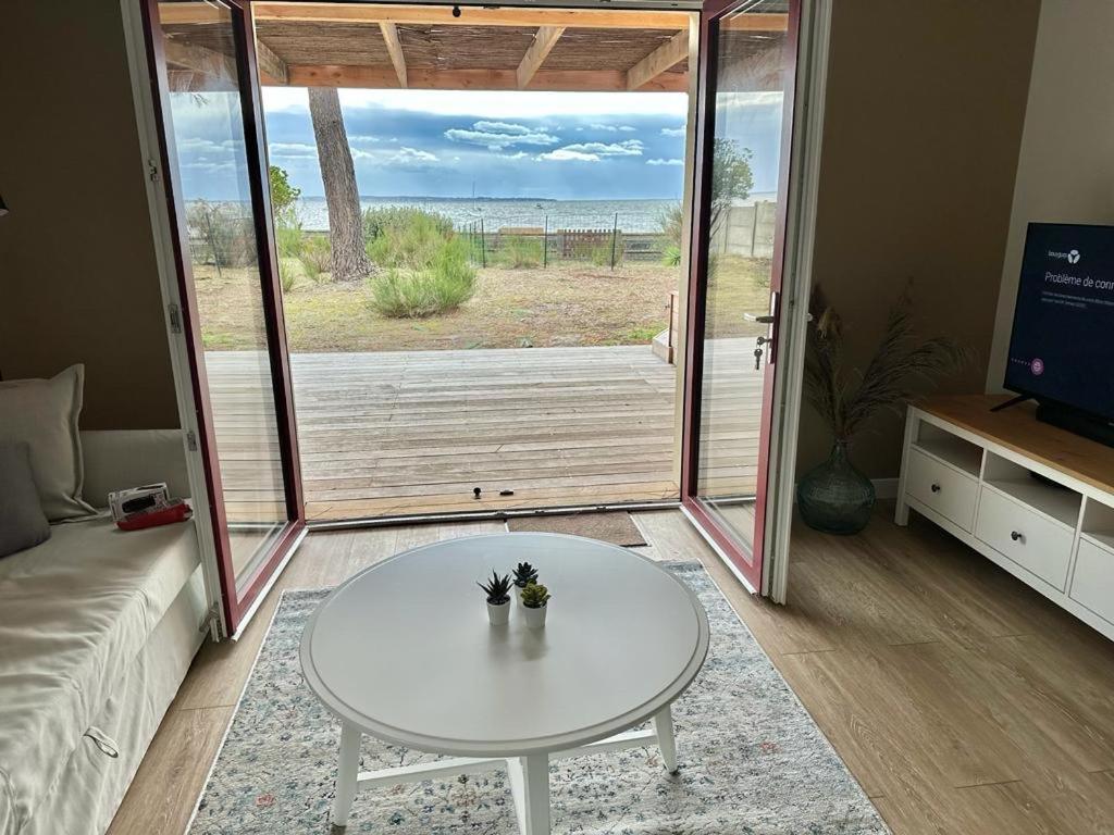 ein Wohnzimmer mit einem Tisch und Meerblick in der Unterkunft Maison première ligne Tocade2 in Andernos-les-Bains