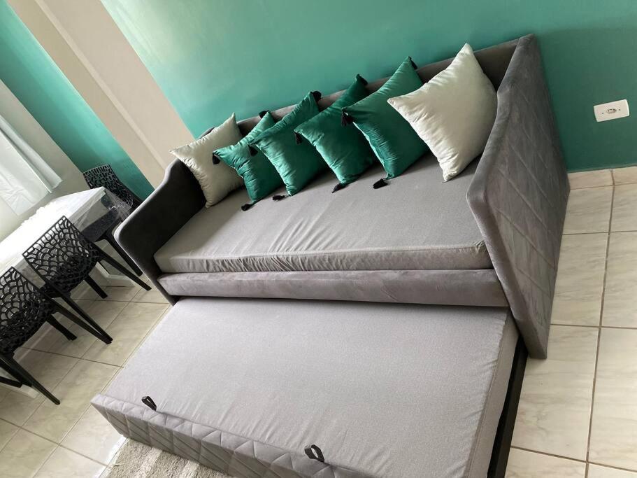 eine Couch mit grünen und weißen Kissen drauf in der Unterkunft Novíssimo apartamento térreo in Votorantim