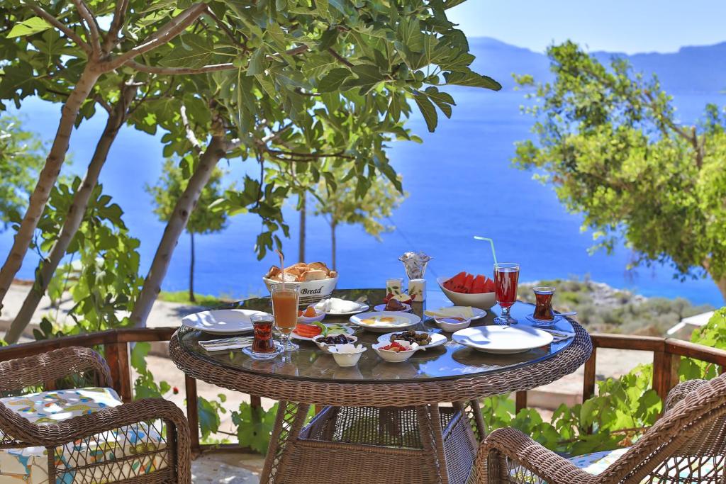 a table with food and drinks on a balcony with the ocean at Hamarat Otel in Kaş