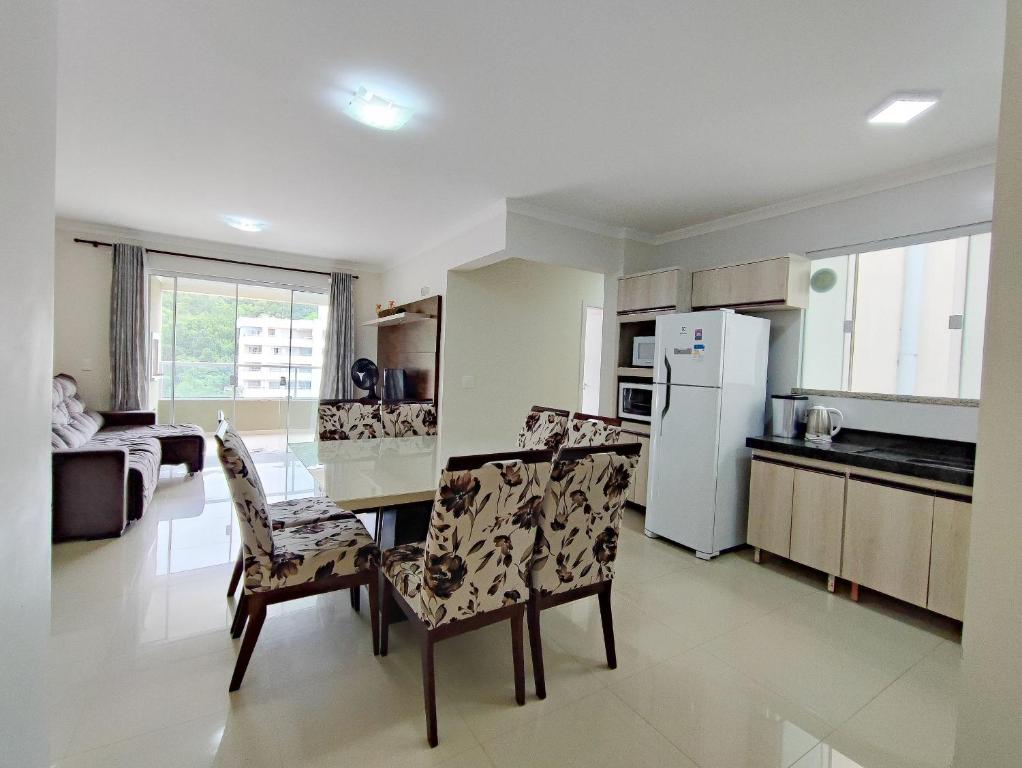 a kitchen with a table and chairs and a refrigerator at Aluguel Apartamento 3 Quartos s 1 Suite Bombas in Bombas