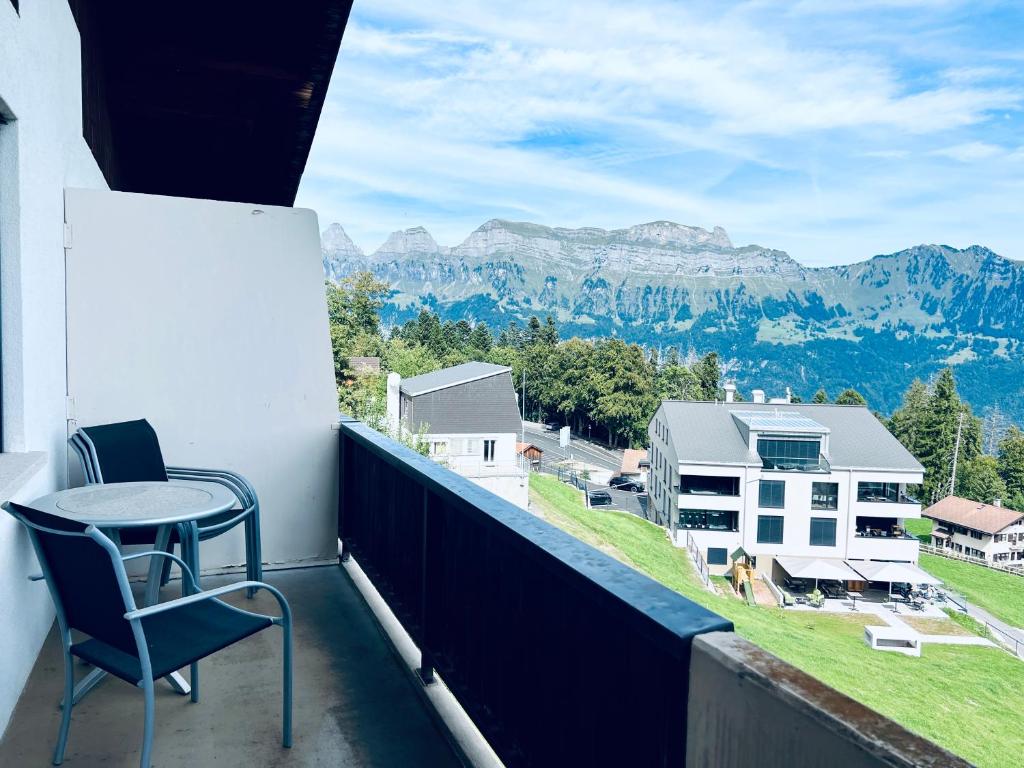 a balcony with a table and chairs and mountains at Panorama Hak - CharmingStay in Flumserberg