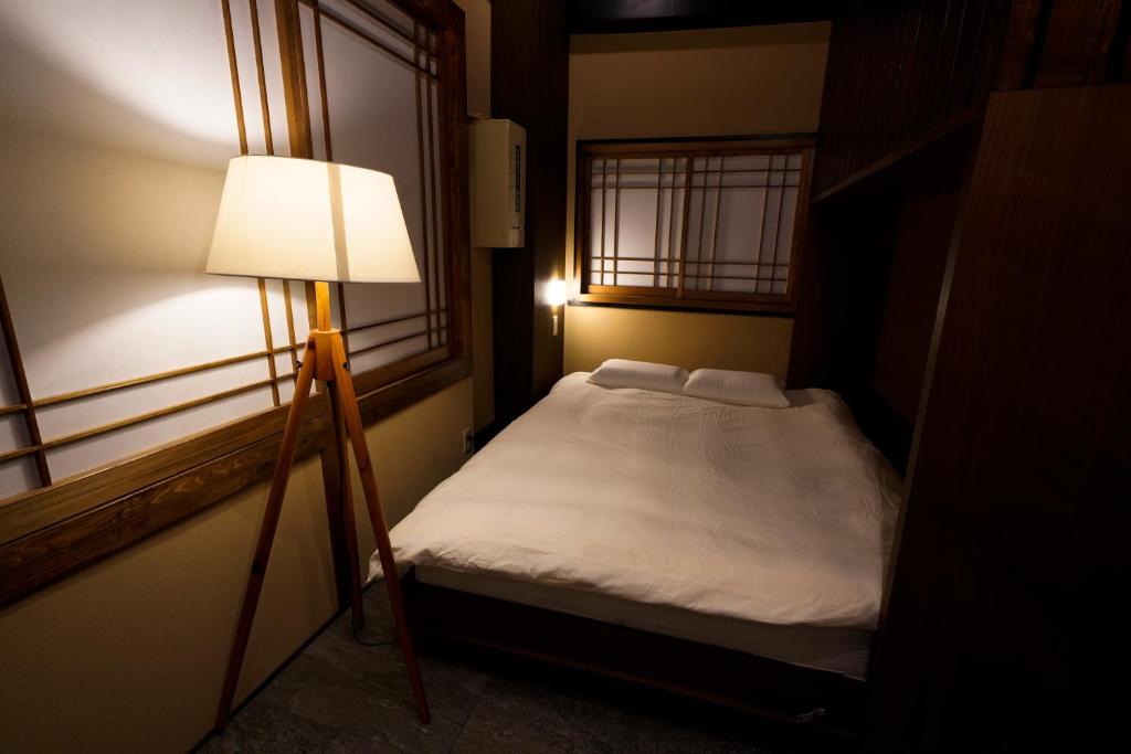 Dormitorio pequeño con cama y lámpara en HOTEL Lee, en Tokio