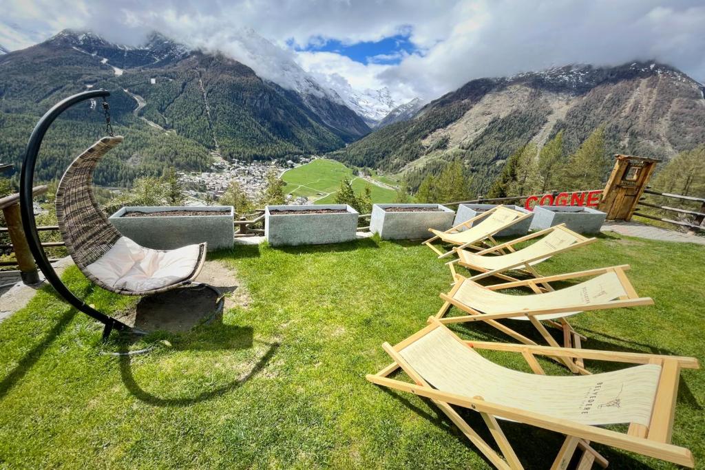 un grupo de sillas sentadas en el césped con montañas en Hotel Belvedere, en Cogne