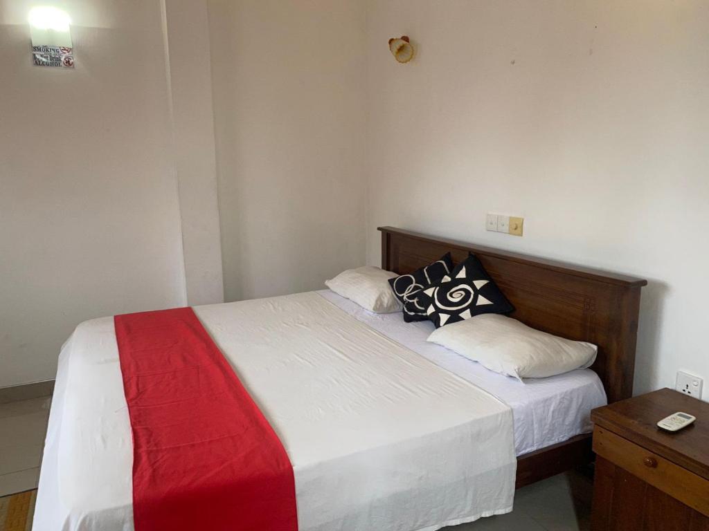 een slaapkamer met een bed met een rode en witte deken bij JJ VILLA ALUTHGAMA in Aluthgama