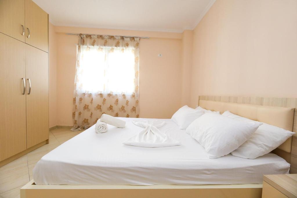 um quarto com uma cama branca e uma janela em Apartment oslo 4 em Vlorë