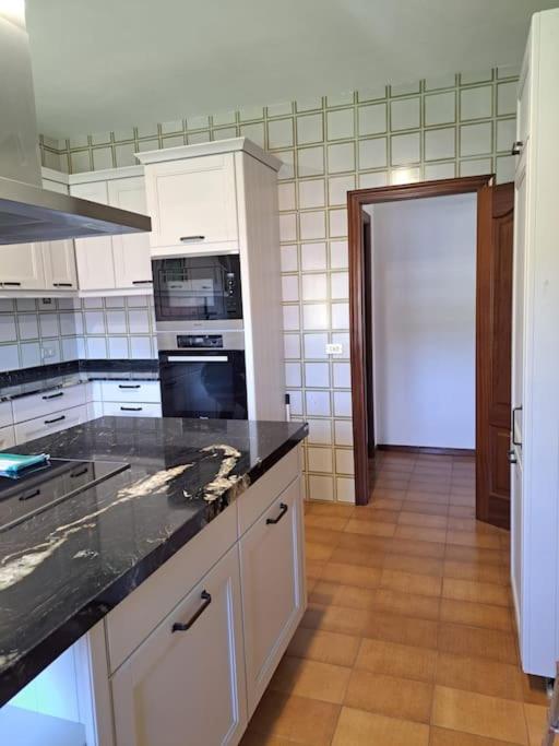 a kitchen with white cabinets and a black counter top at Casa Ares in Cee