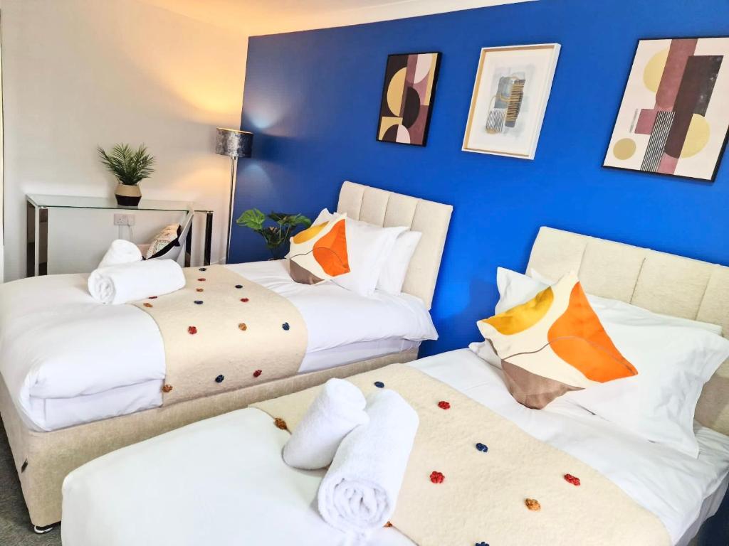 2 camas en una habitación con una pared azul en 1 Bed Central Serviced Accommodation with Balcony in Stevenage Free WIFI by Stay Local Home Welcome Contractors Business Travellers Families en Stevenage