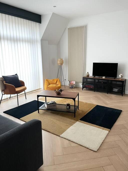 uma sala de estar com um sofá, uma mesa e uma televisão em Cocon d'Alsace em Colmar