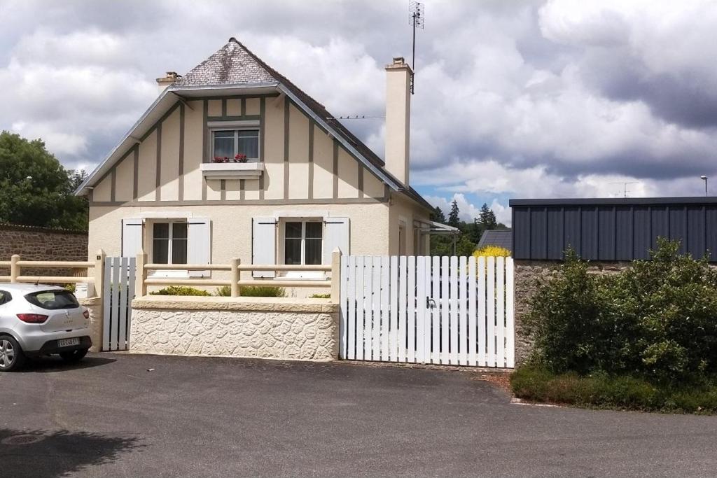 een wit huis met een wit hek en een auto bij LAtelier de la Rivière in Belle-Isle-en-Terre