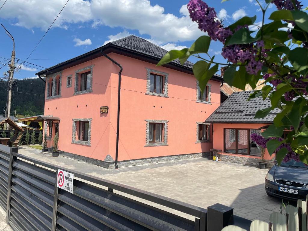 ein rosa Haus mit einem Zaun davor in der Unterkunft Casa Rarăului in Câmpulung Moldovenesc