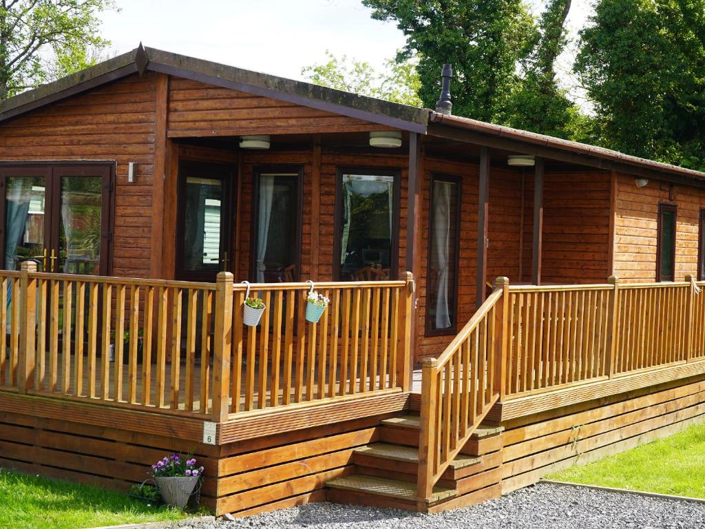 a wooden cabin with a porch and a deck at Roe Deer Lodge in Newton Stewart