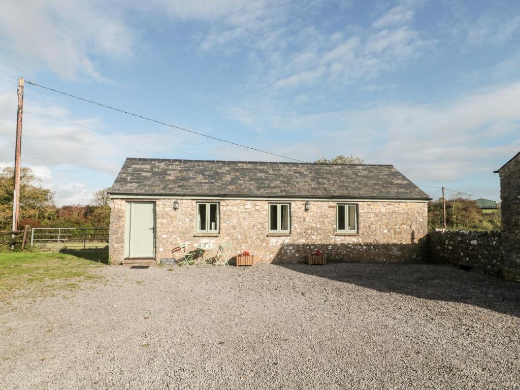 a stone house with a gravel driveway at Ash Tree Cottage in Cowbridge