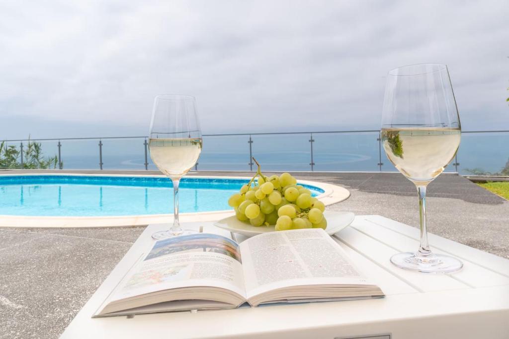 a table with a book and two glasses of wine at Belo Mar in Arco da Calheta