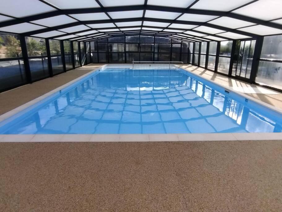 une grande piscine intérieure d'eau bleue dans l'établissement Cottage Nature Piscine partagée Vue Vilaine, à Arzal