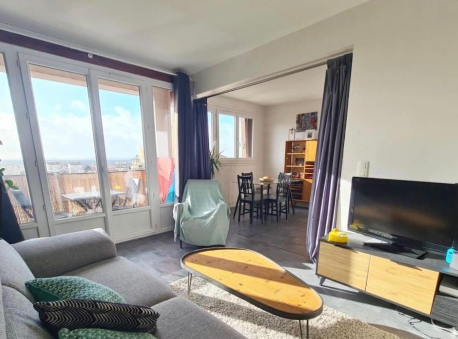 a living room with a couch and a television and a table at Appartement à 20mn de Paris et 40mn de Disney in Fontenay-sous-Bois