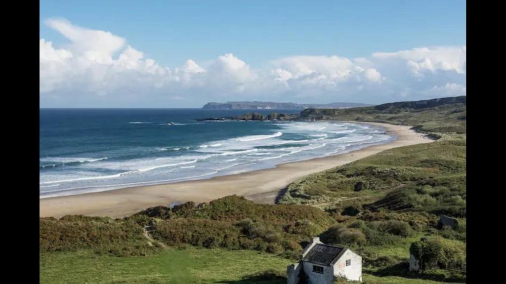 a view of a beach with a house and the ocean at McConaghys Glenside Farmhouse Whitepark Bay in Ballintoy