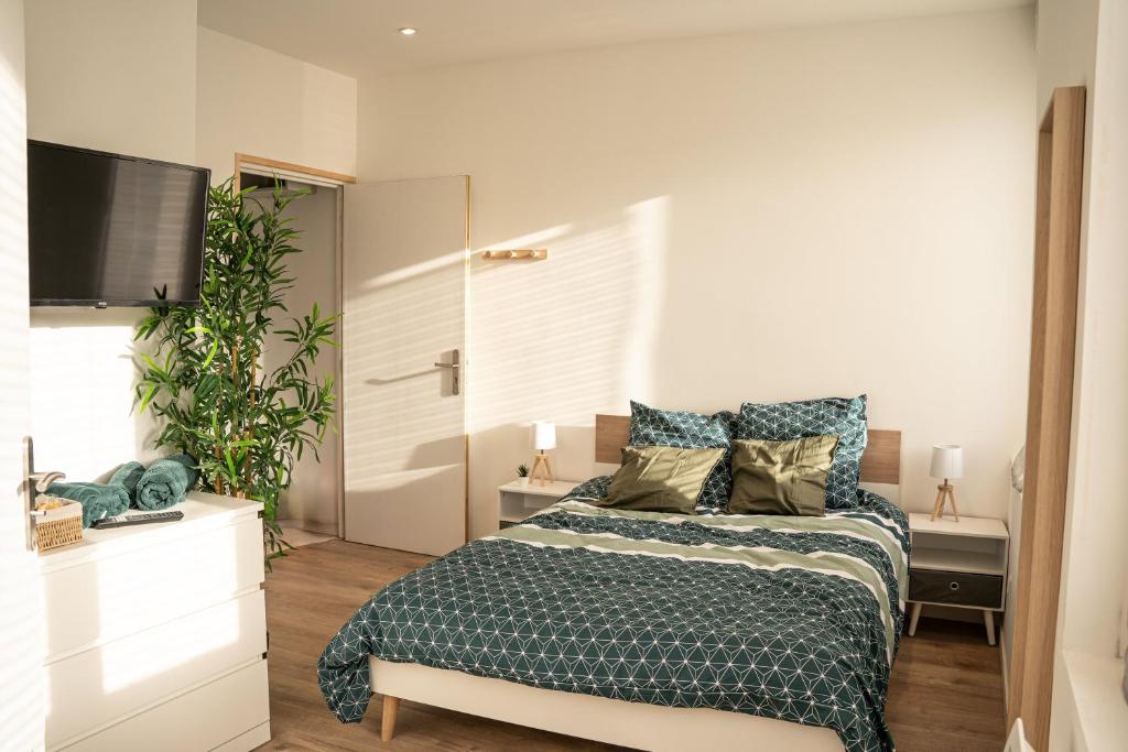 a bedroom with a bed and a flat screen tv at TC Residences - Charmant Appartement in Saint-Quentin