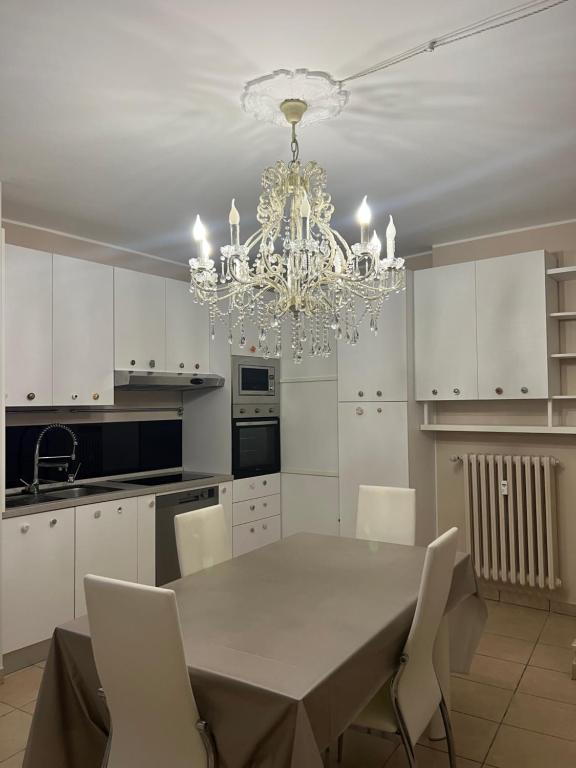 a white kitchen with a dining table and a chandelier at Tevere 20 House in Monza