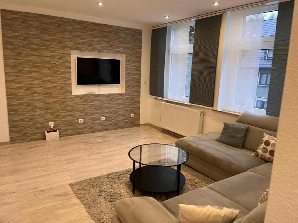 salon z kanapą i telewizorem na murze z cegły w obiekcie New York by D&J Apartments Altenessen Nord w Essen