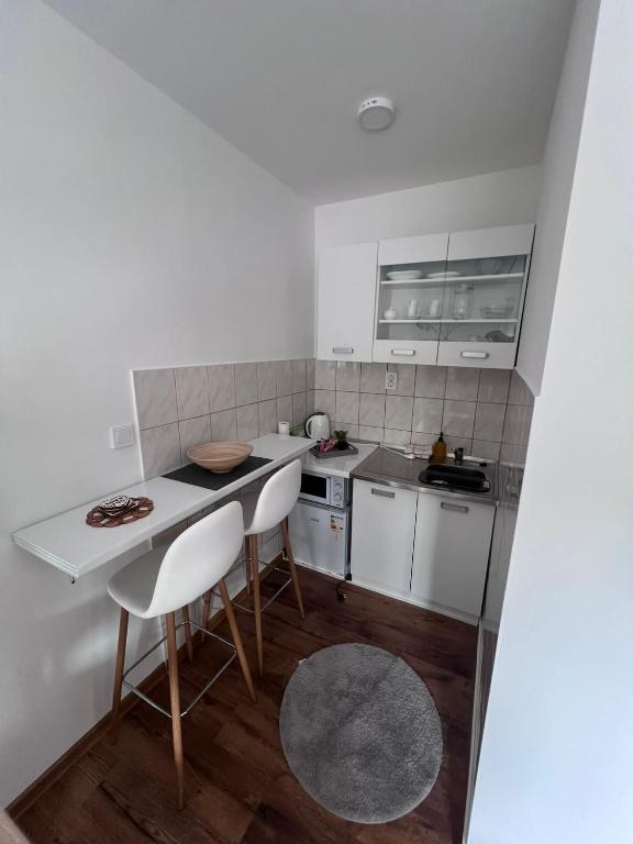 a small kitchen with white cabinets and white chairs at Golden joy in Sarajevo