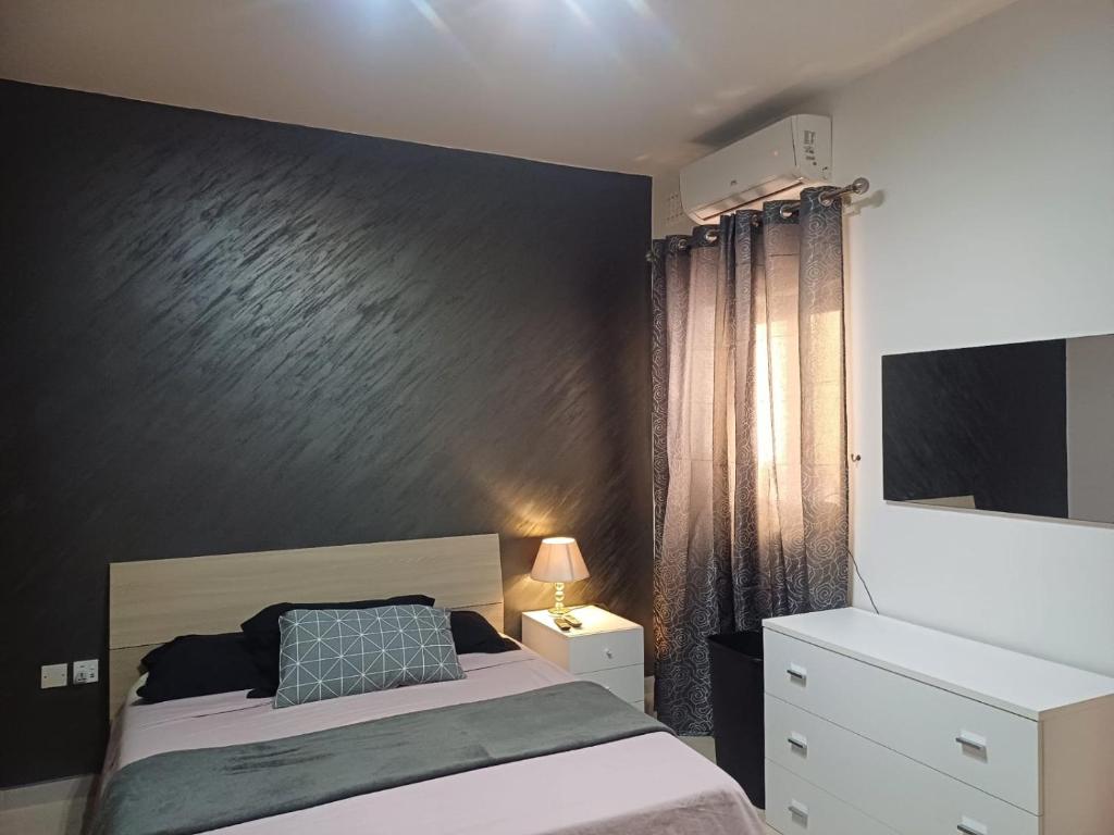 1 dormitorio con cama y pared negra en Modern Private Rooms in an apartment, en St Paul's Bay