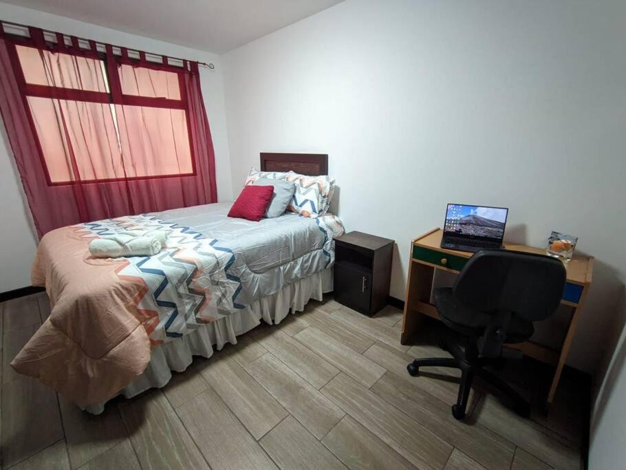 1 dormitorio con 1 cama y escritorio con ordenador en Guatemala, departamento ciudad capital zona 12. en Guatemala