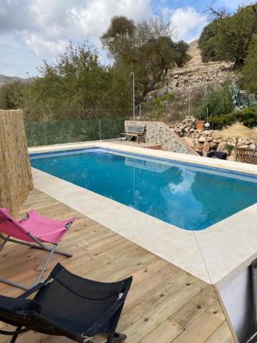 einen Pool mit 2 Stühlen und einem rosa Stuhl in der Unterkunft Maison Andalouse avec piscine in El Almendral