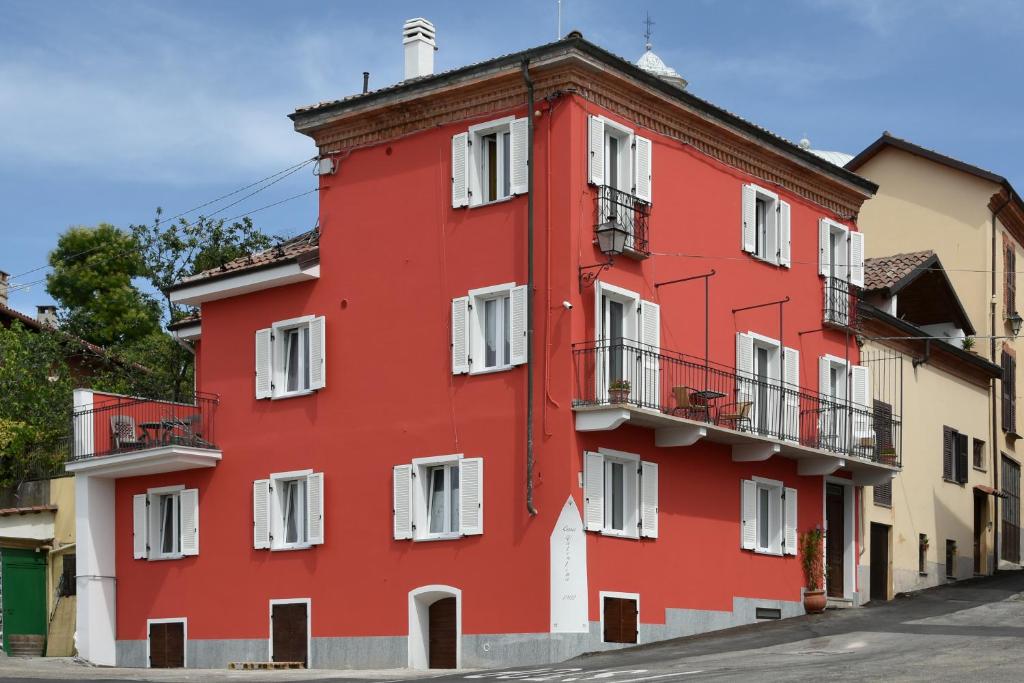 un bâtiment rouge avec des fenêtres blanches sur une rue dans l'établissement Casa Valentina 1902, à Montegrosso dʼAsti