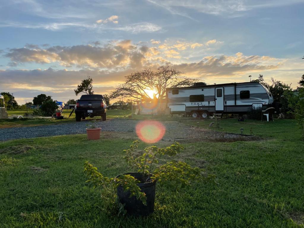 um reboque e um camião estacionados num campo com o pôr-do-sol em Camper de Camaseyes em Aguadilla