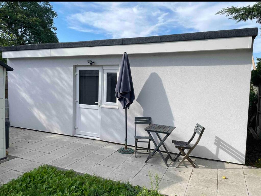 uma garagem branca com duas cadeiras e um guarda-sol em Remarkable 1-Bed Outhouse Studio in Dagenham em Dagenham