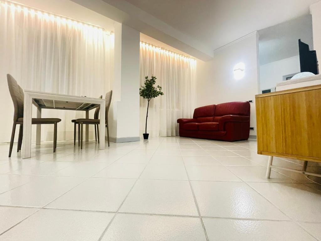 Amikales Rooms في بادوفا: غرفة معيشة مع طاولة وأريكة حمراء
