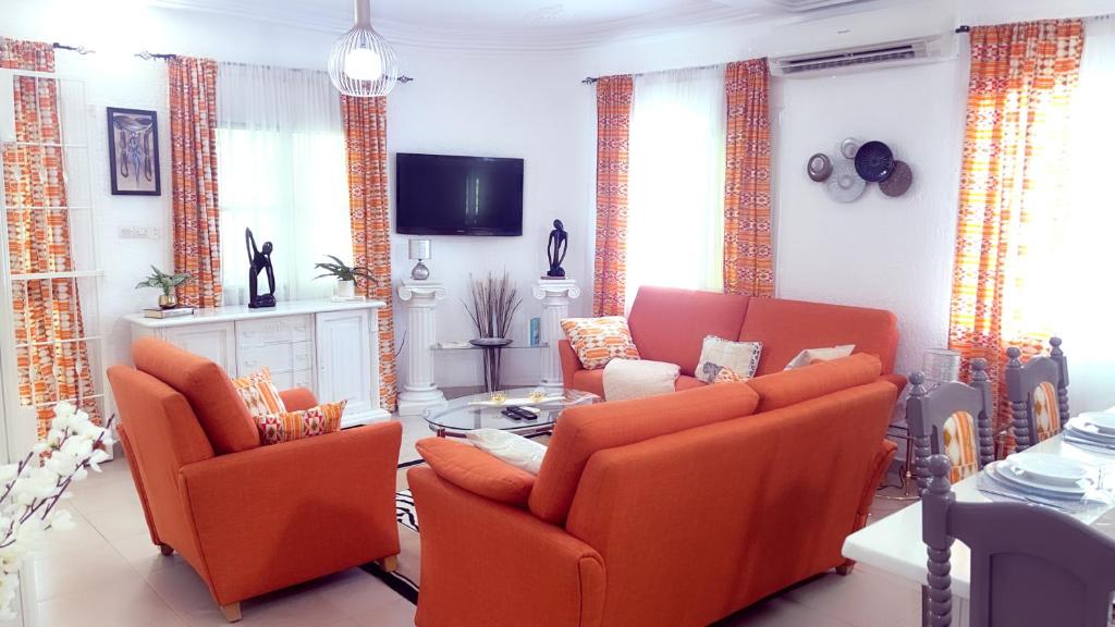 a living room with orange chairs and a tv at Villa 3 Chambres Salon Adidogomé in Fazao