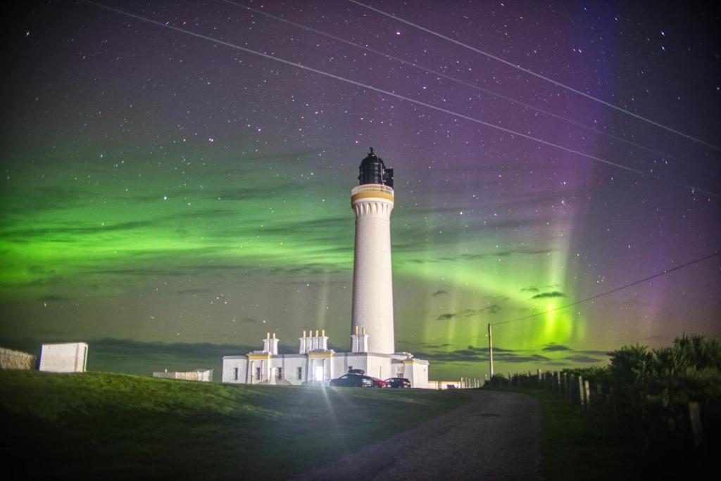 a lighthouse with the aurora in the sky behind it at Highway in Lossiemouth