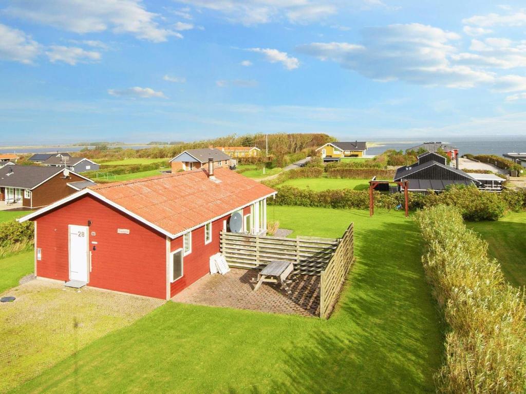 a red house with a bench in a yard at Three-Bedroom Holiday home in Lemvig 1 in Lemvig
