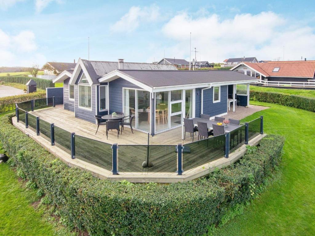 a tiny house with a large deck on a lawn at Three-Bedroom Holiday home in Lemvig 6 in Lemvig