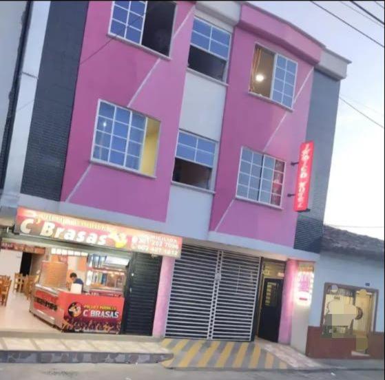 un edificio rosa con un camión de comida delante de él en Hotel Indigo en Cartago
