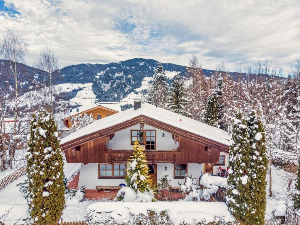 a house covered in snow with trees and mountains at Schergrub in Kirchberg in Tirol